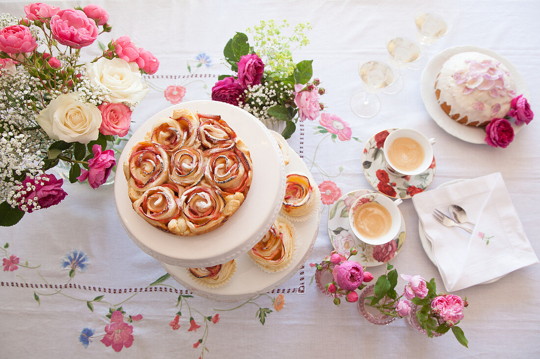 Apfelrosen-Kuchen, Kuppeltorte und Kaffee auf Tisch mit Rosendekoration