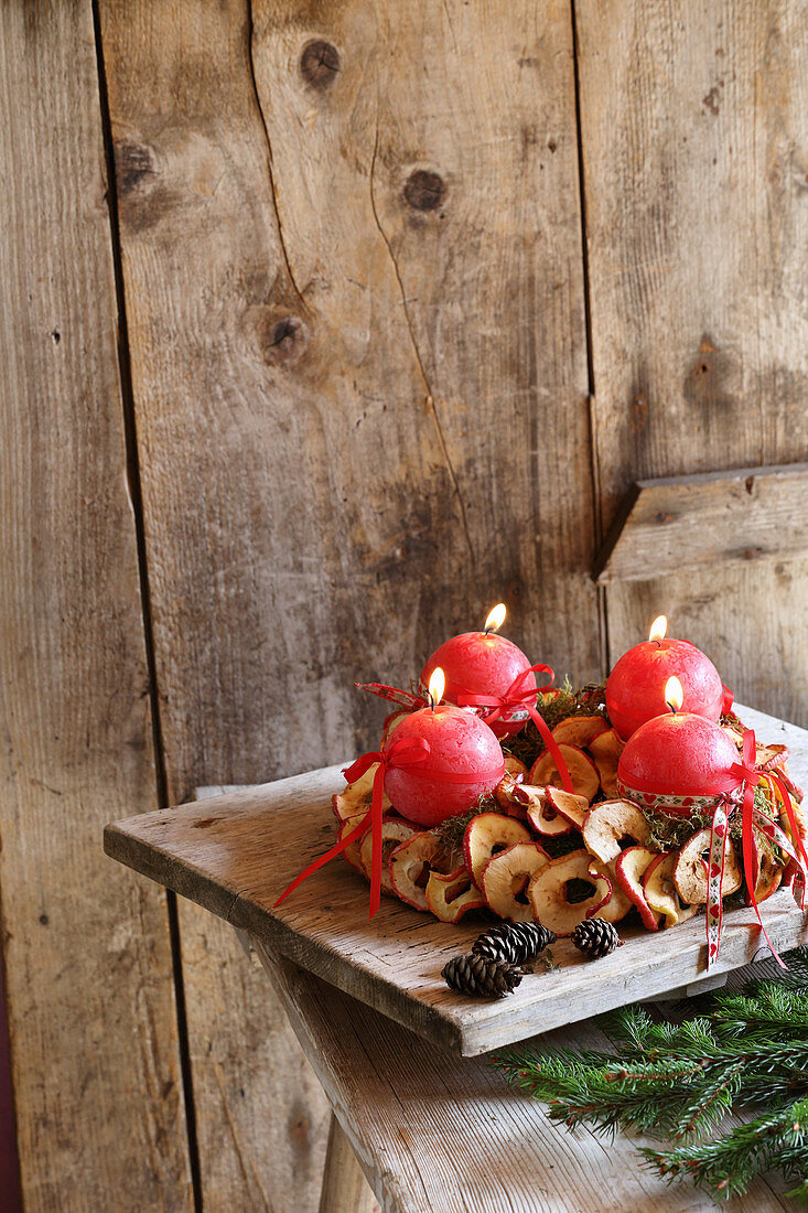 Adventskranz mit vier brennenden Kerzen und getrockneten Apfelringen