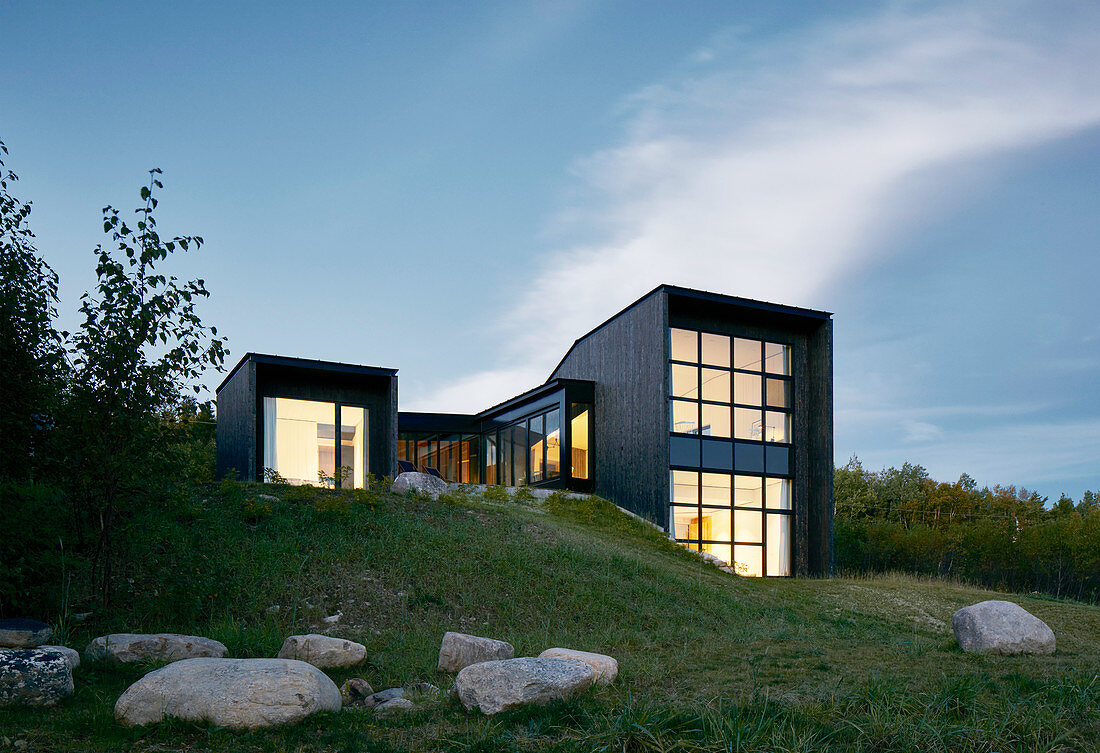 Cubist architect-designed house at twilight with illuminated glass walls