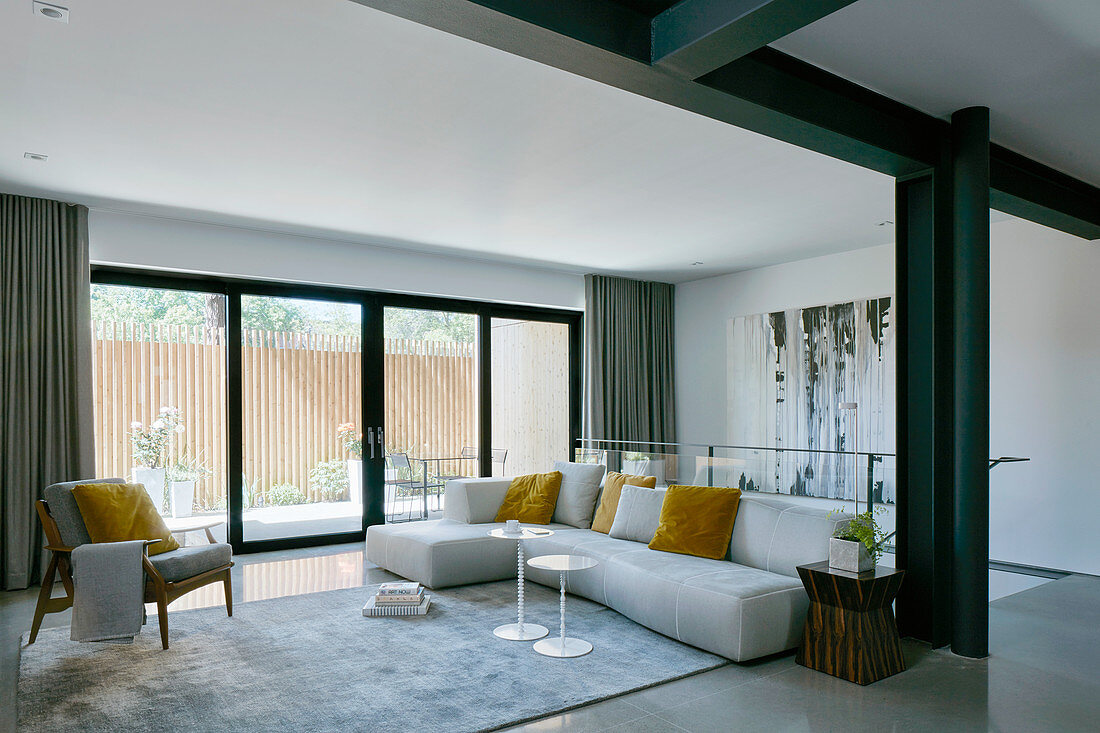 White sofa with yellow scatter cushions in living room with black beams