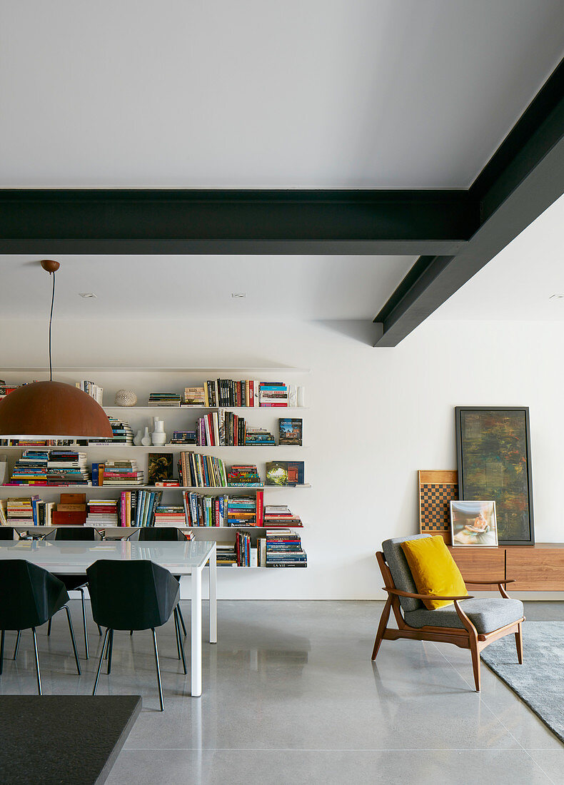 Moderner Wohnraum mit Esstisch vor der Bücherwand