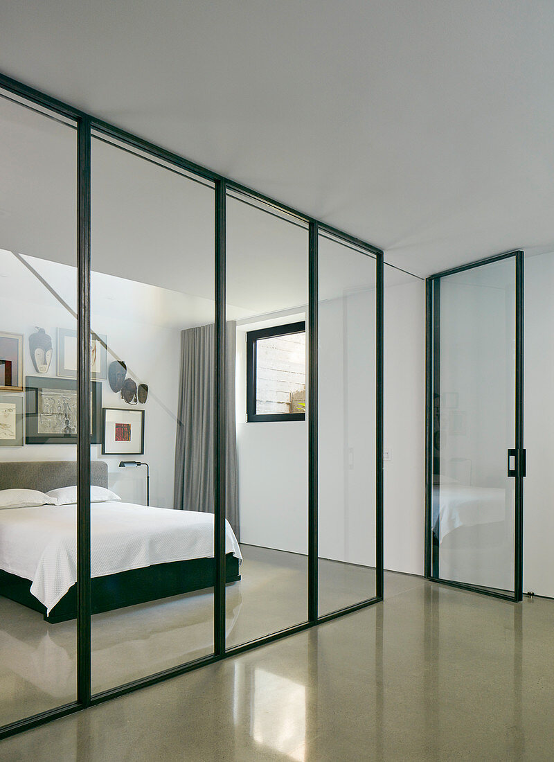 Glass and steel partition wall with door screening bedroom