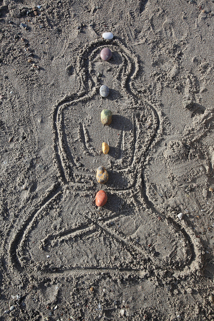 Symbolic image with pebbles placed on chakras of the human body