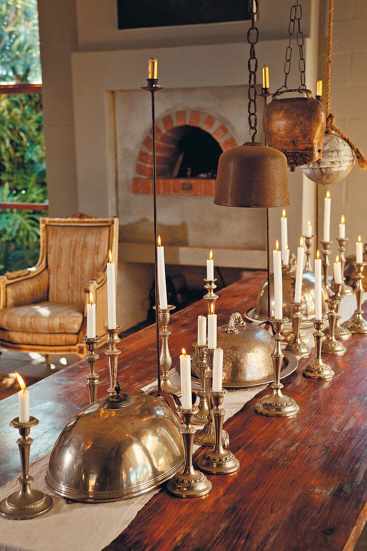 Silberne Kerzenleuchter und Servierglocken auf dem Holztisch