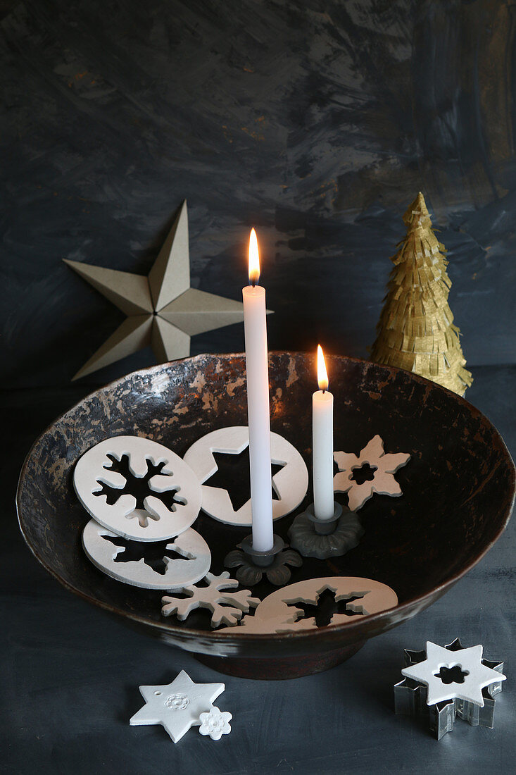 Zwei brennende Kerzen in einer Schale mit Anhängern aus Modelliermasse