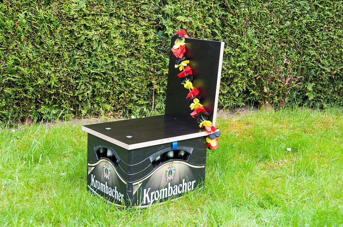 Selbstgebauter Bierkastenstuhl mit Blumenkette in Deutschland-Farben