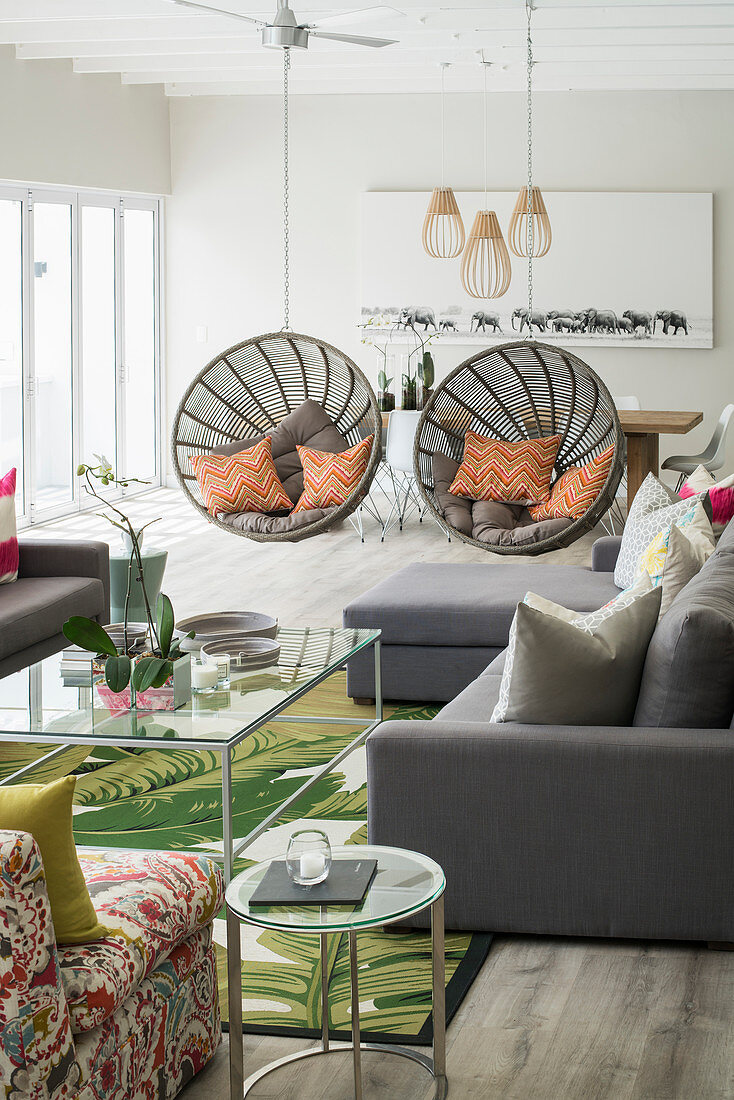 Two round hanging chairs forming partition in open-plan interior
