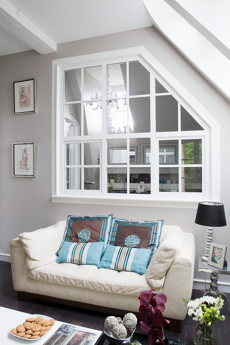 weiße Ledercouch mit Kissen unter Innenfenster im Wohnzimmer