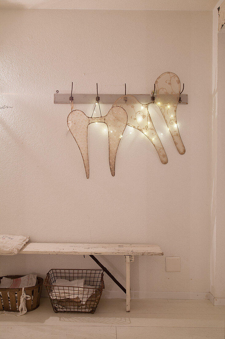 Two pairs of wings and fairy lights hung on coat rack