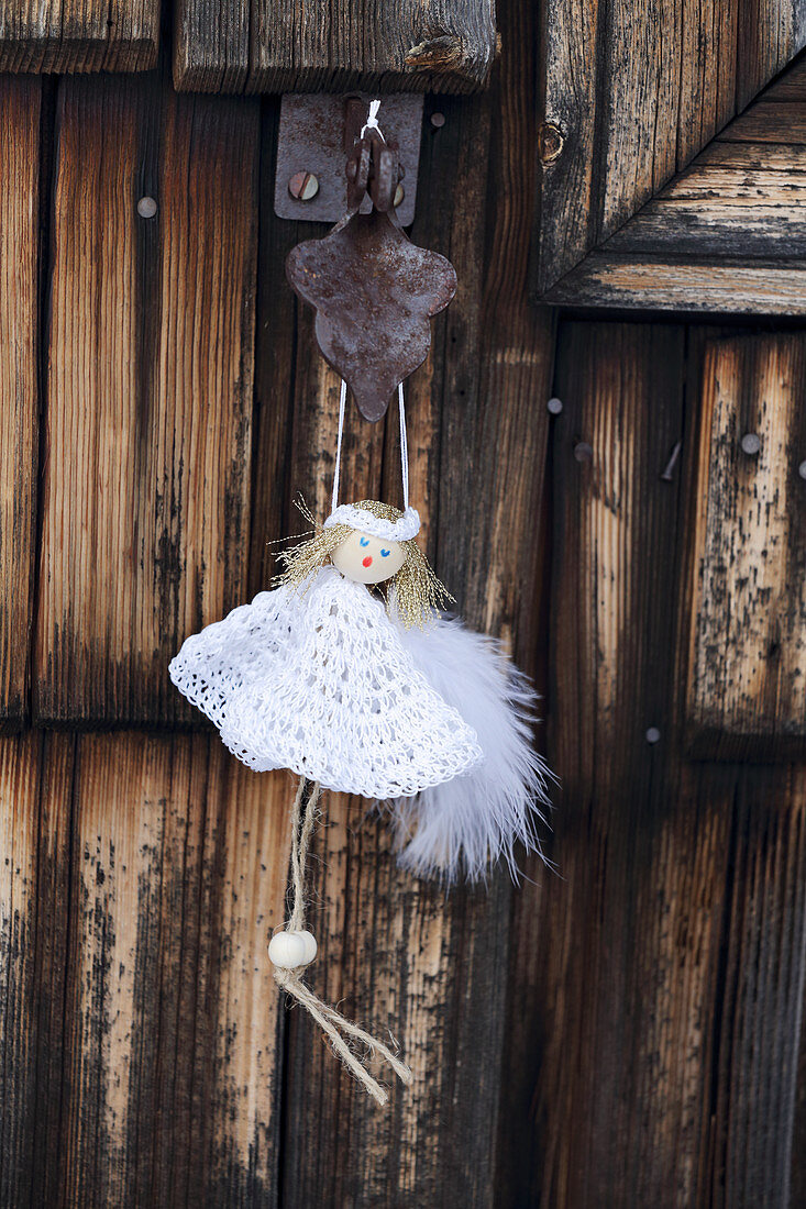 Handmade angel in white dress hung from wooden door