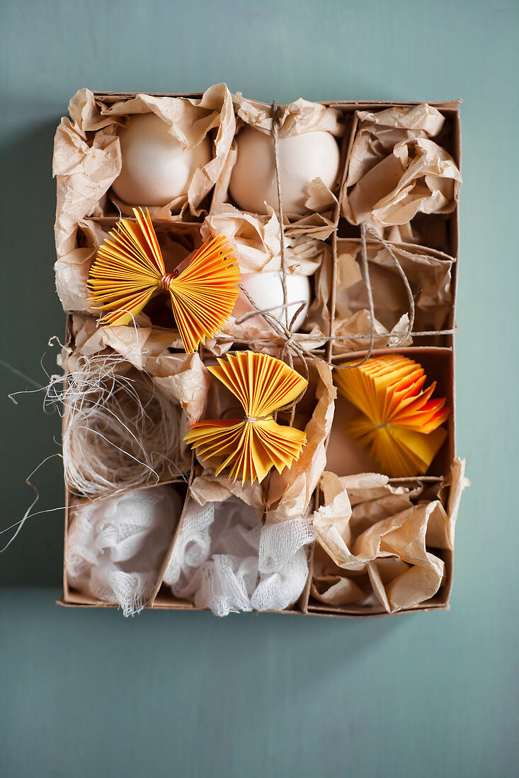 White eggs and yellow paper rosettes in box