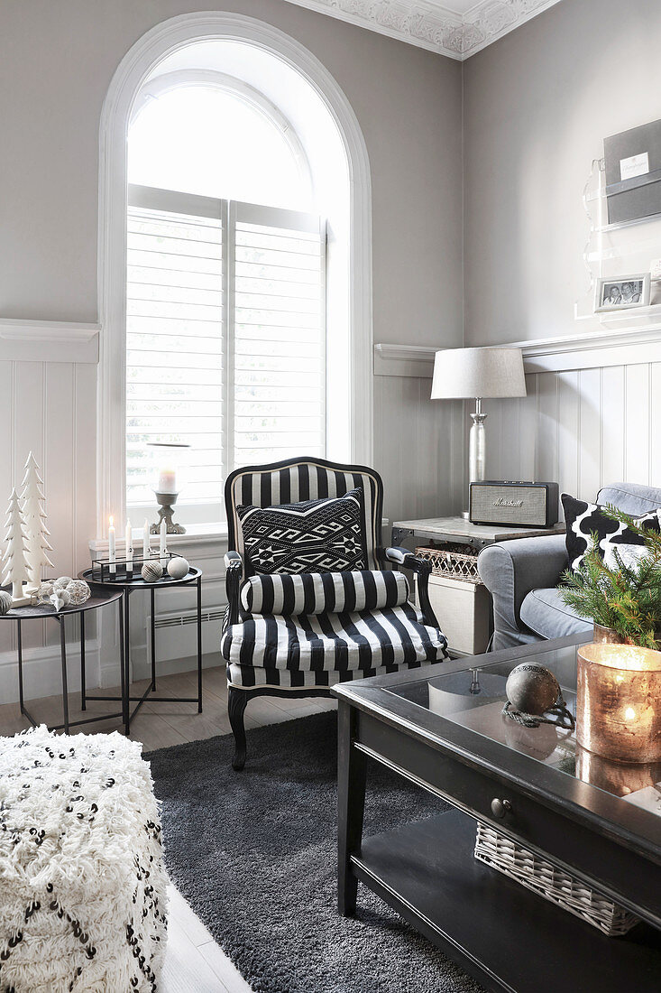 Schwarz-weiß gestreifter Sessel vorm Bogenfenster im Wohnzimmer