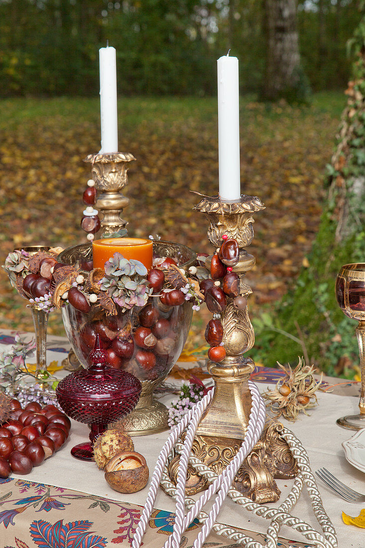 Antique candlesticks and glass goblet decorated with horse chestnuts