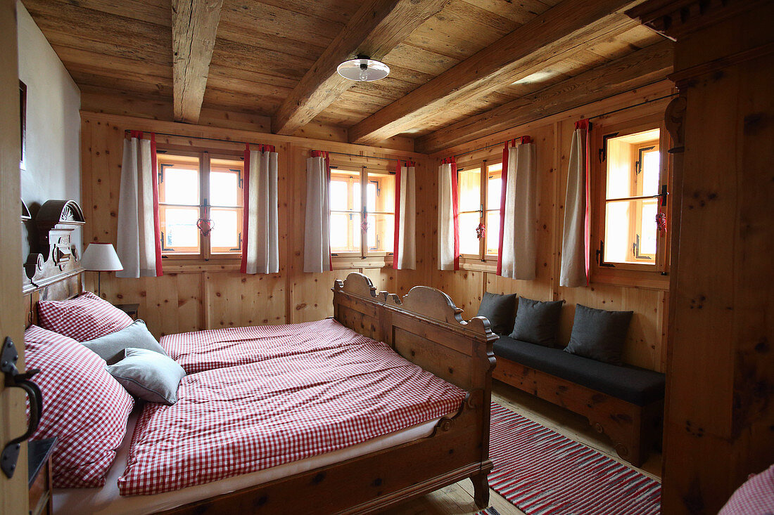 Doppelbett mit rot-weiß karierter Bettwäsche in einer Holzhütte