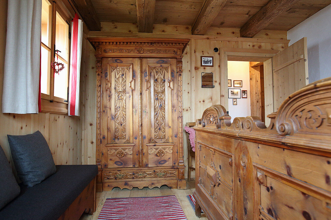 Kleiderschrank und Doppelbett mit Holz-Fußteil im Hütten-Schlafzimmer