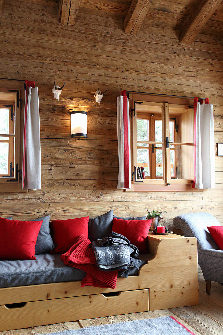 Red and grey cushions in wooden bed in chalet