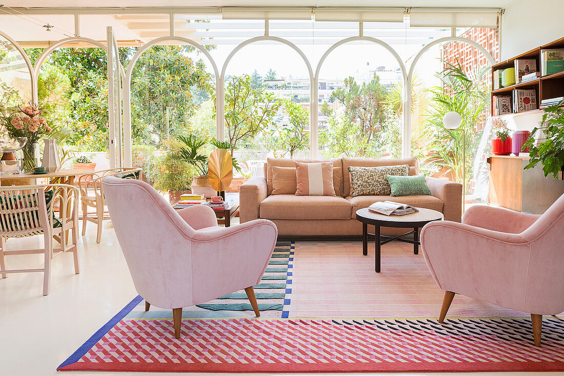 Living room in pastel shades with glass wall leading to Mediterranean garden