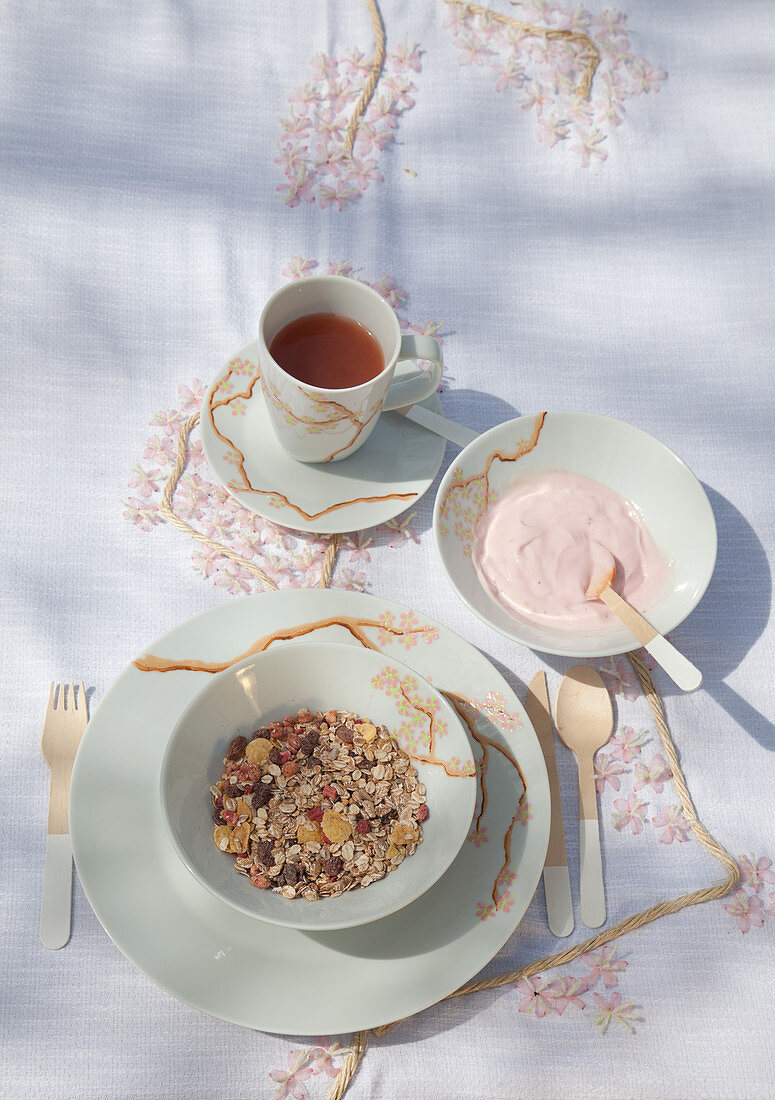 DIY-Tischdecke und Frühstücksgeschirr mit Kirschblütenmotiv, Tee, Joghurt und Müsli