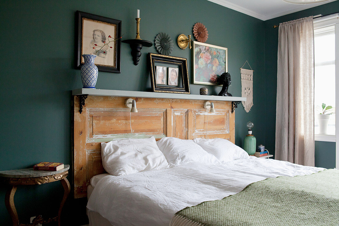 Doppelbett mit Betthaupt aus alter Tür im Schlafzimmer mit grünen Wänden