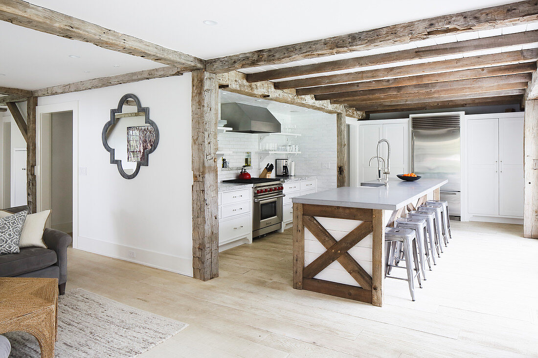 Offener Wohnraum mit Holzbalken und offene Küche mit Kücheninsel