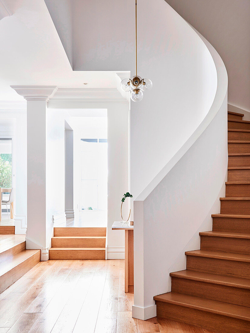 Wooden spiral staircase and white walls in the stairwell