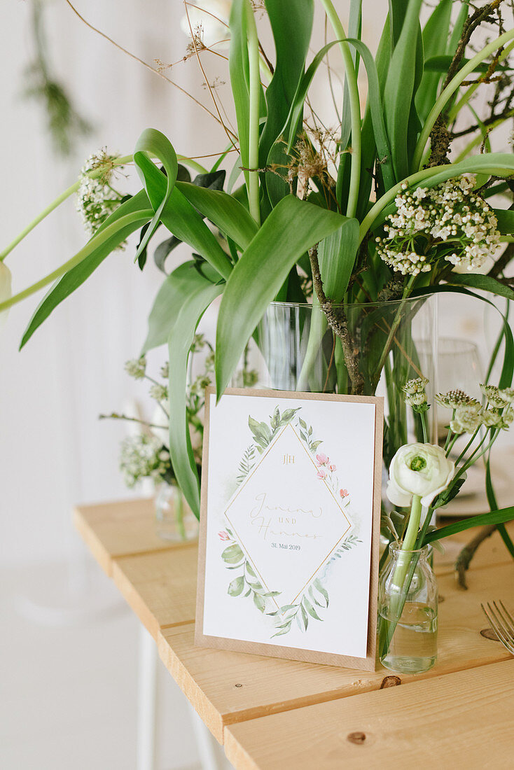 Frühlingsblumen in Glasvase und Hochzeitskarte