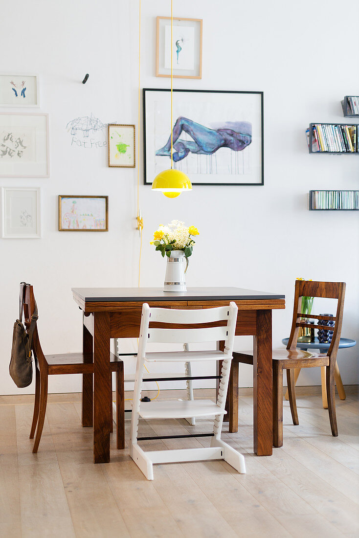 Yellow pendant lamp providing splash of colour above square dining table and wooden Tripp Trapp chair