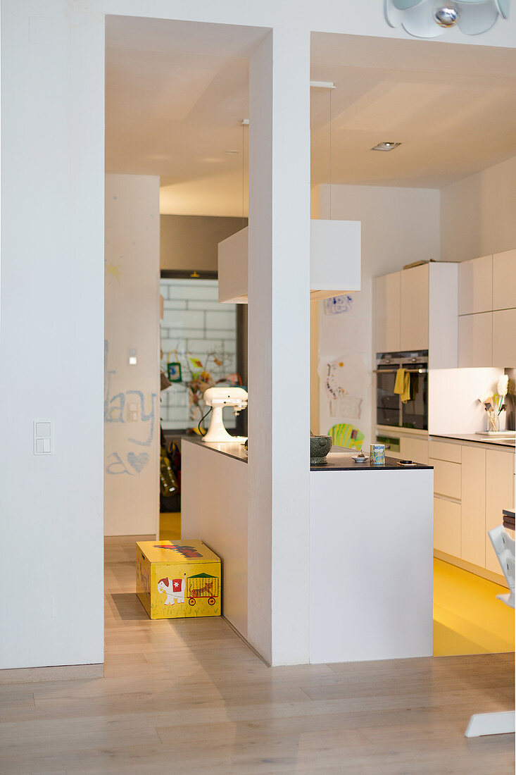 White kitchen furnishings and bright yellow floor in open-plan kitchen area