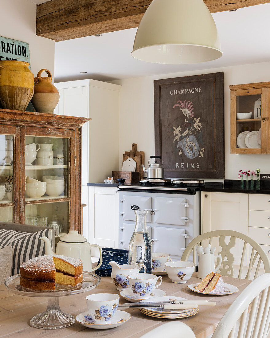 Vintage, französisches Schild über Herd in rustikaler Küche, Teegeschirr und Kuchen auf Tisch
