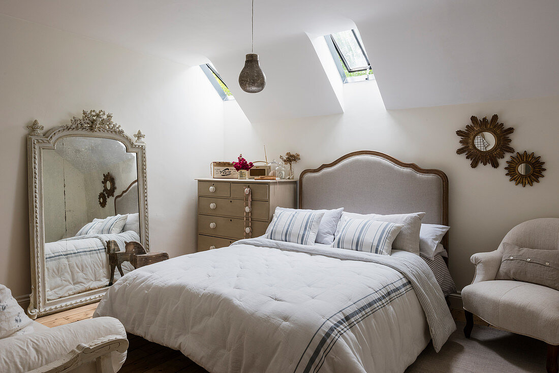 Verzierter französischer Spiegel und Doppelbett im Gästezimmer mit Dachschräge