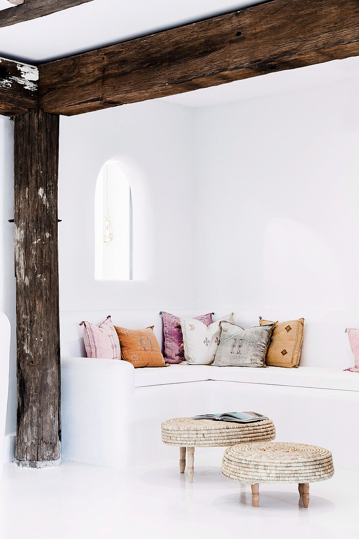 White seating area with colorful cushions and arched window