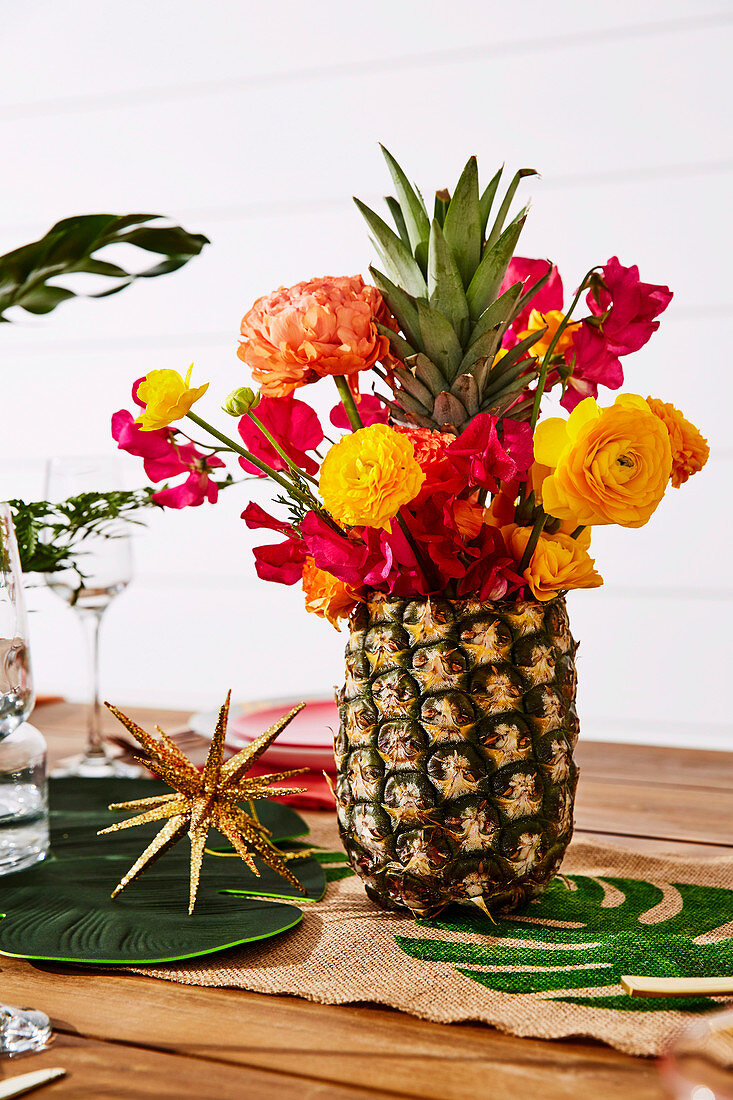 Blumenstrauß in Ananas-Vase auf weihnachtlich dekoriertem Tisch