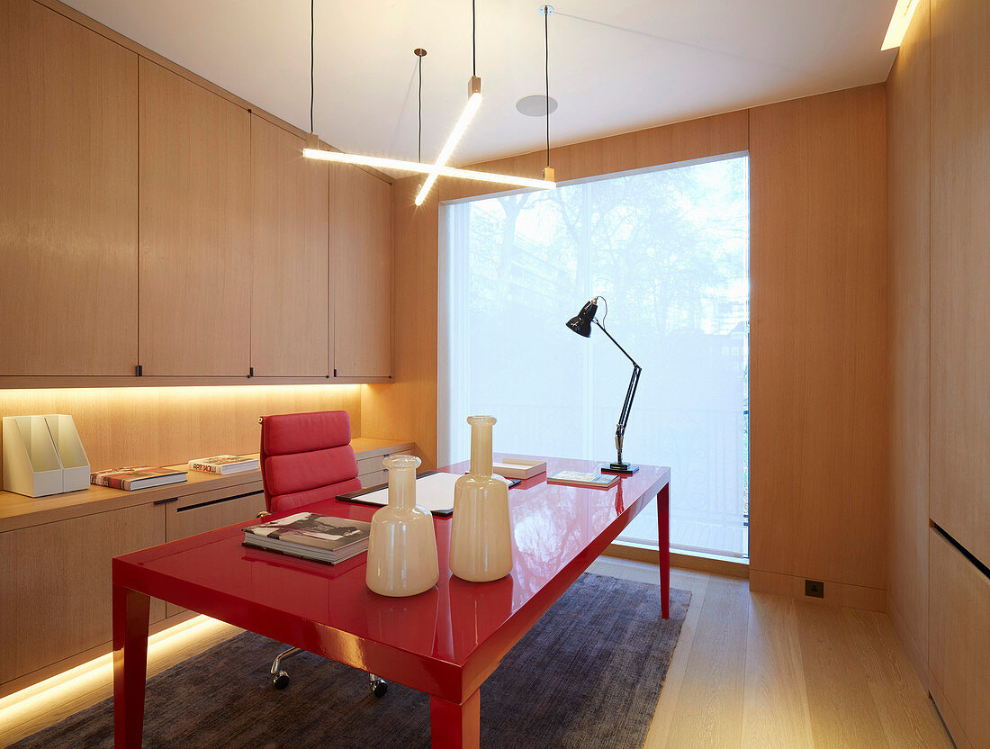 Elegantes Arbeitszimmer mit rotem Schreibtisch und Einbauschrank
