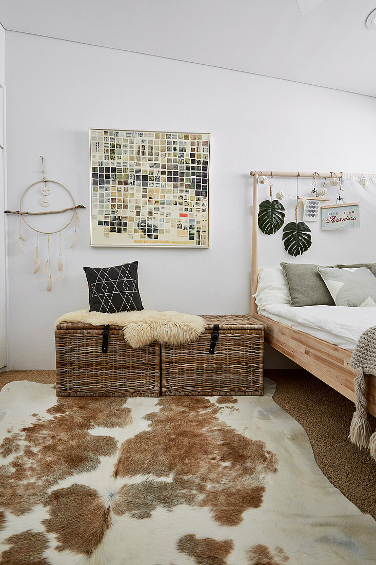 Rattentruhen mit Schaffell neben Bett und Tierfellteppich im Schlafzimmer