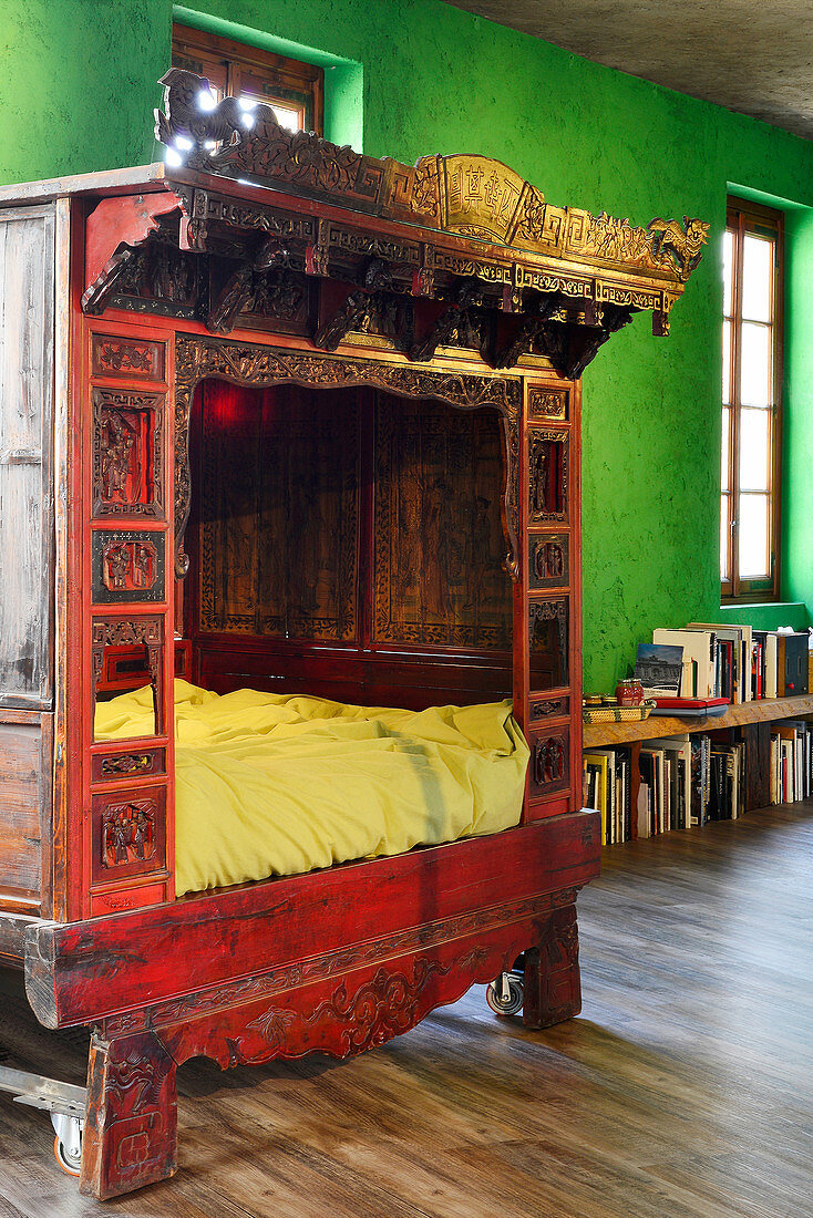 Antique Chinese wedding bed against green wall in renovated loft apartment