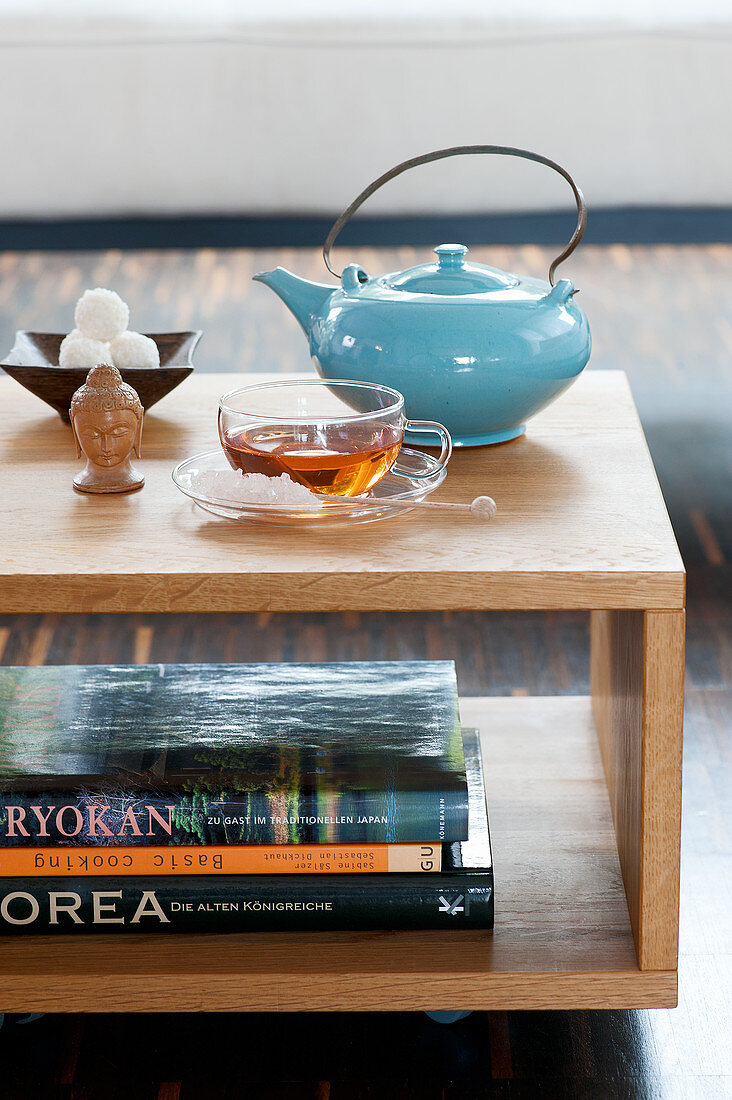 Teetasse, Teekanne und Buddhakopf auf Couchtisch
