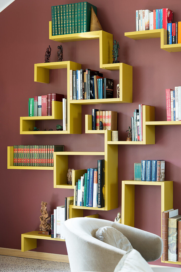 Gelbes Designer-Bücherregal an dunkelroter Wand