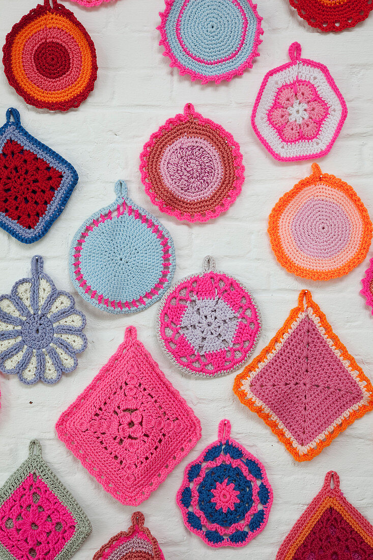 Many crocheted doilies on white brick wall