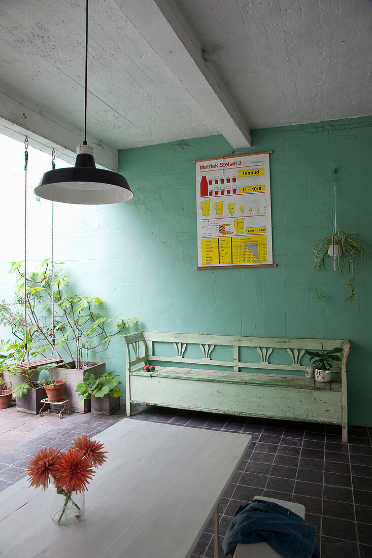 Holzbank und Pflanzen auf überdachter Terrasse mit grüner Wand