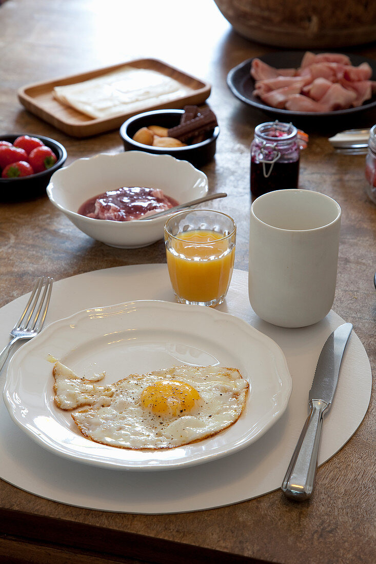 Gedeckter Frühstückstisch mit Spiegelei und Orangensaft