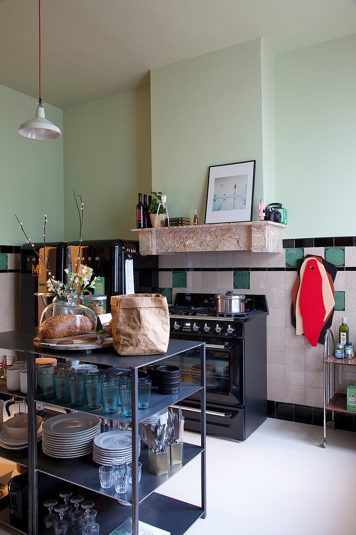 View into kitchen with crockery on open shelves and mint-green walls