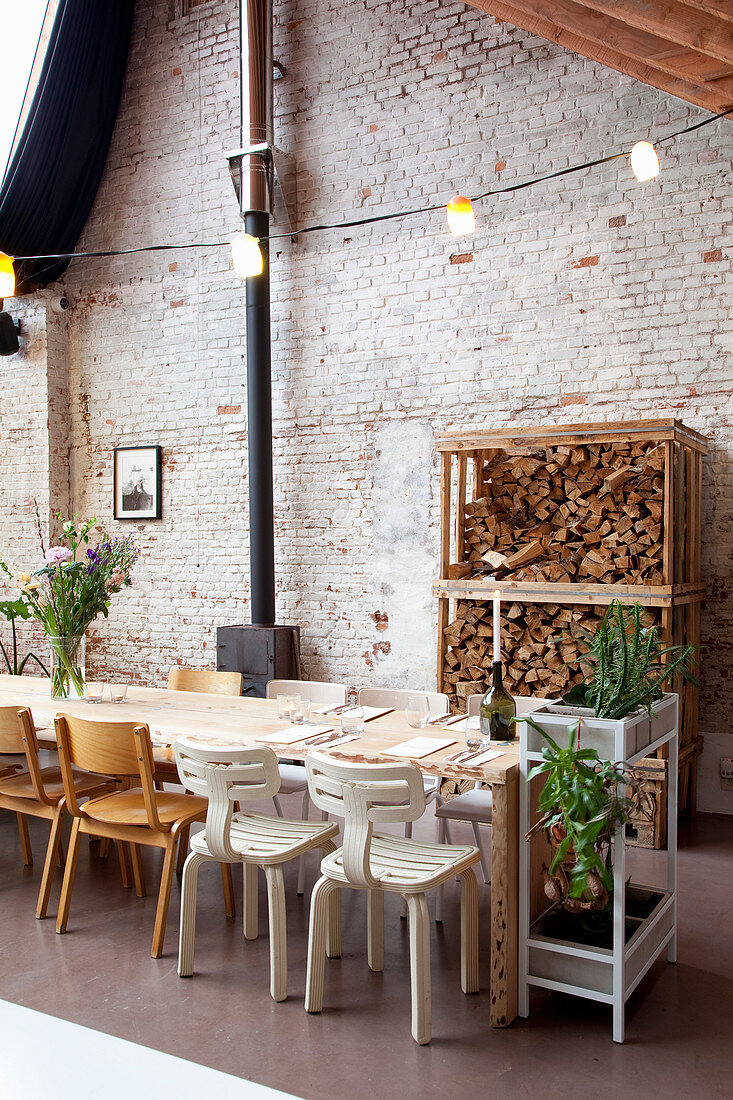 Set table, chairs and firewood rack against brick wall