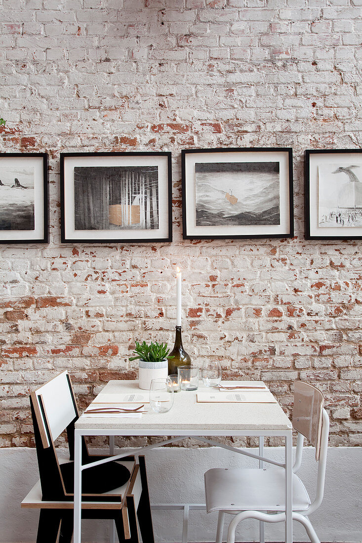 Table for two in front of photos on brick wall