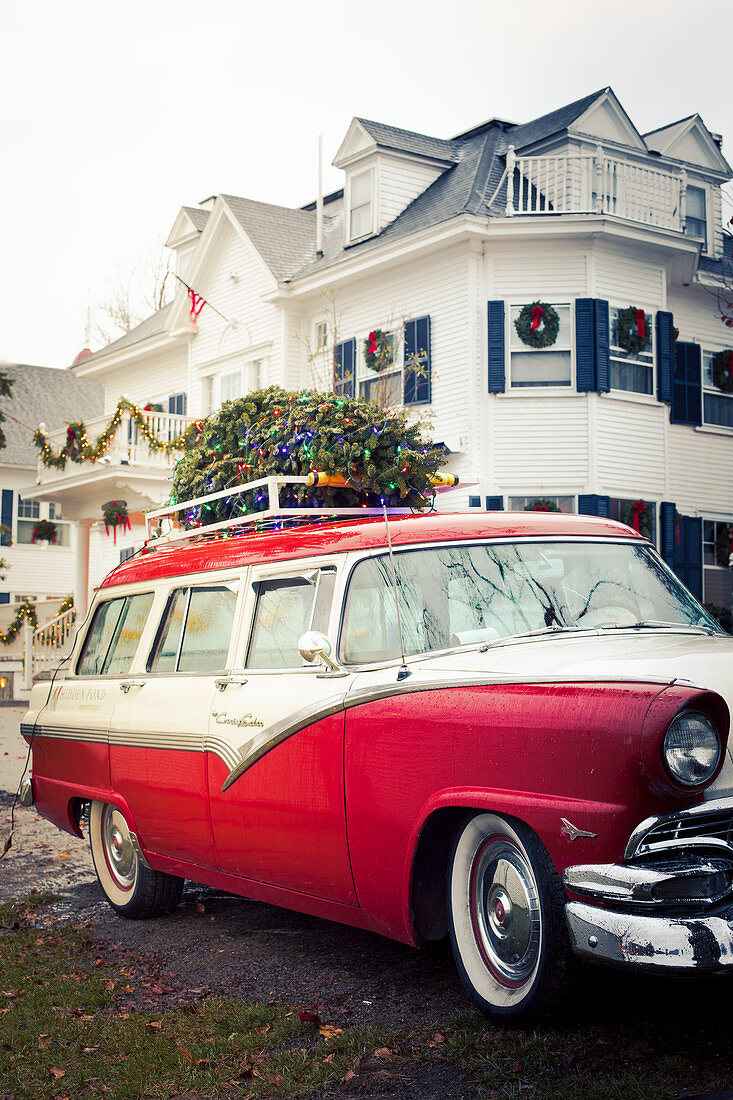 Oldtimer mit geschmücktem Weihnachtsbaum auf Dachträger