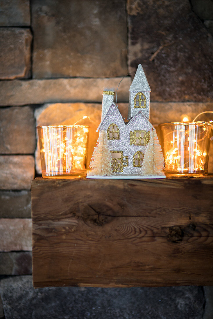 House-shaped Christmas decoration and fairy lights in glass vases