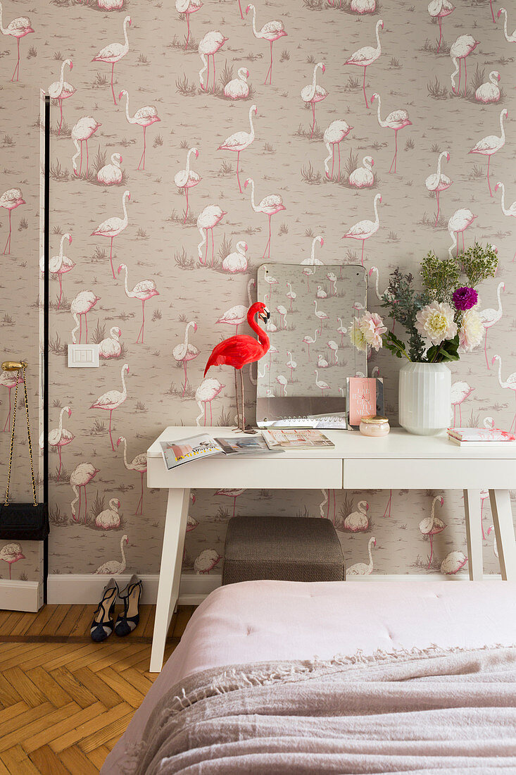 Flamingo ornament on table against flamingo-patterned wallpaper