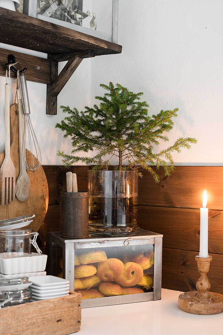 Lit candles in front of box of pastries and small Christmas tree