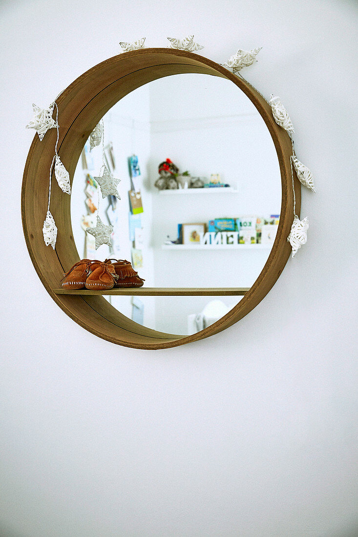 Round wall mirror with children's shoes and Christmas decorations