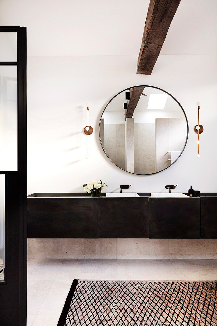 Bathroom with round wall mirror and double vanity made of dark wood