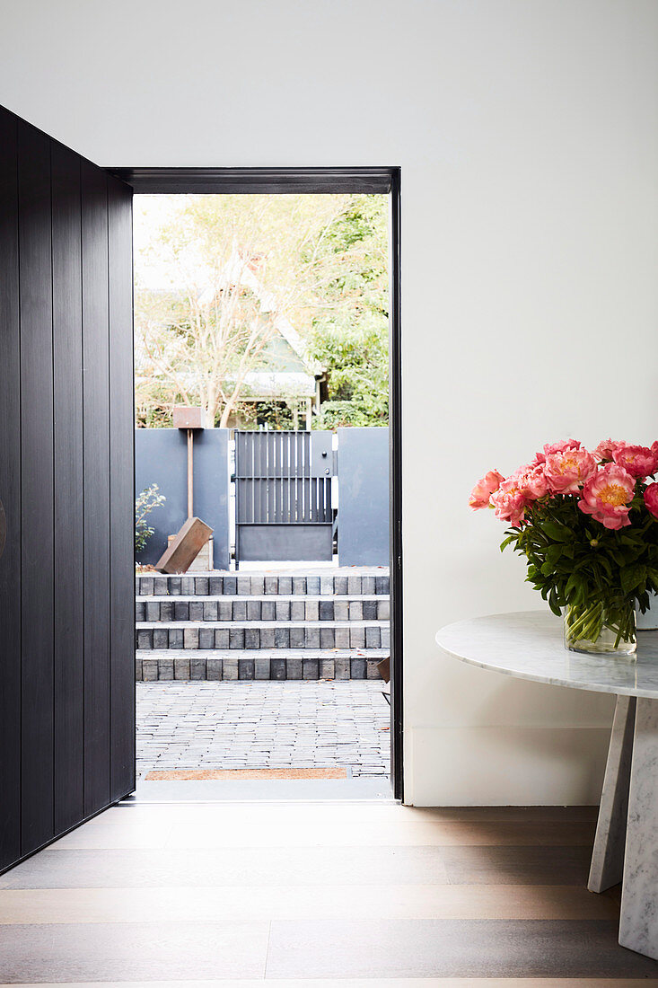 Round table with a lush bouquet of flowers next to an open front door